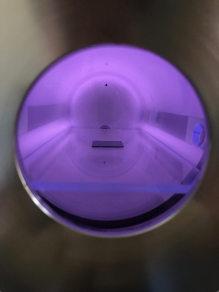 Violet argon plasma glowing over a thin-film coupon in a Tergeo plasma cleaner