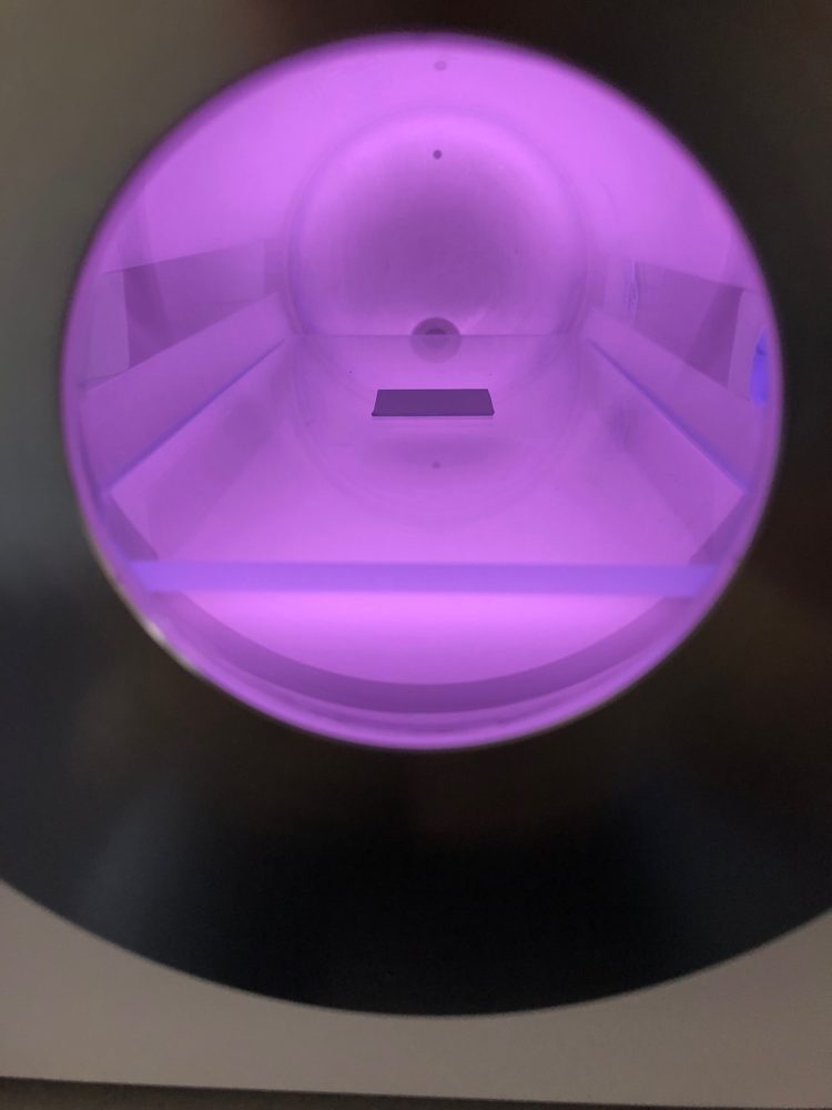 Magenta hydrogen plasma glowing over a thin-film coupon in a Tergeo plasma cleaner