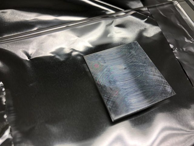 Parylene coated aluminum part with rainbow interference colors before plasma etching
